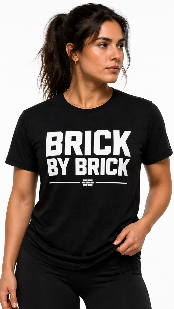 Woman wearing a black t-shirt with 'BRICK BY BRICK' text on a white background