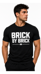 Man wearing a black t-shirt with 'BRICK BY BRICK' text on a white background